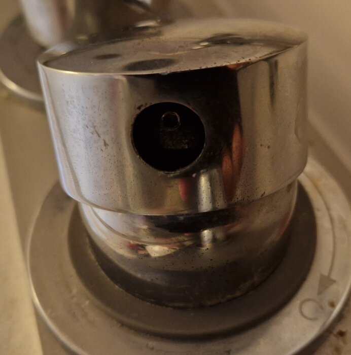 Närbild av en smutsig, använd sprinklerhuvud i rostfritt stål med slitage och droppar.