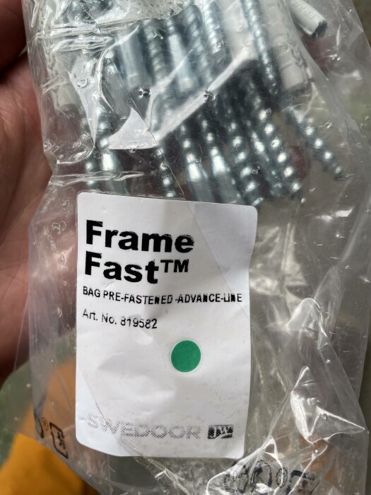 Plastpåse med metallföremål, etikett med "Frame Fast", grön punkt, artikelnummer, tillhör Svedoor.