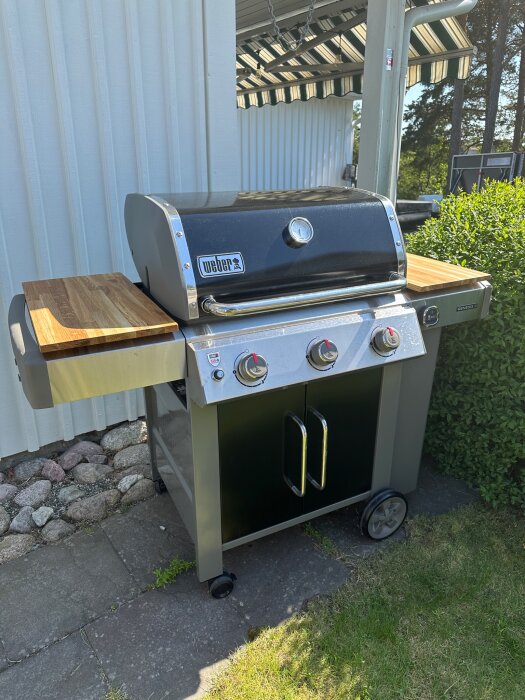 Weber gasolgrill utomhus med sidobord och termometer under blå himmel.