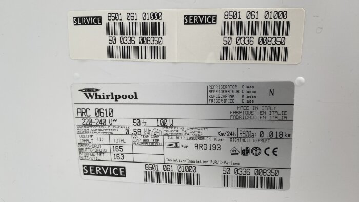 Etiketter med teknisk information och servicenummer på en Whirlpool enhet, troligen en kylskåp eller frys.