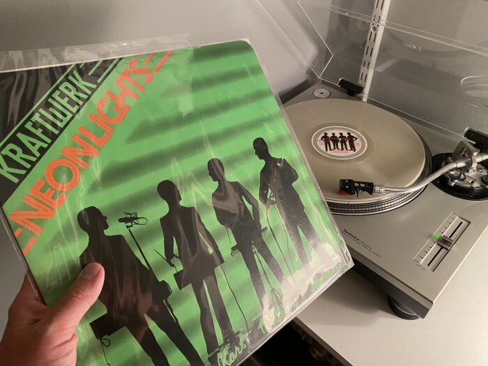 Vinylskiva av Kraftwerk "Neon Lights" på skivspelare, Technics skivtallrik, musikuppspelning i hemmiljö.