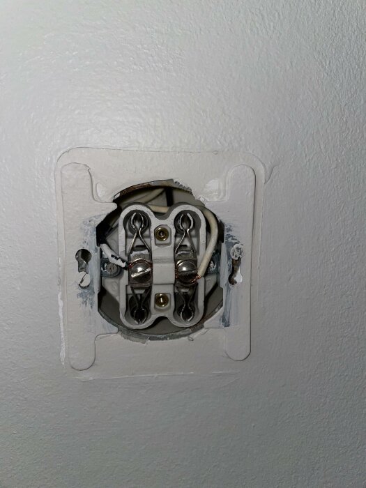Oavslutad eluttaginstallation i vägg, med synliga ledningar och skruvanslutningar, utan lock.