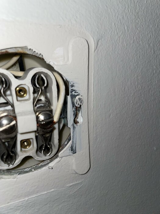 Öppen eluttag, kablar exponerade, skruv synlig, väggplatta tar bort, säkerhetsrisk, underhåll behövs.