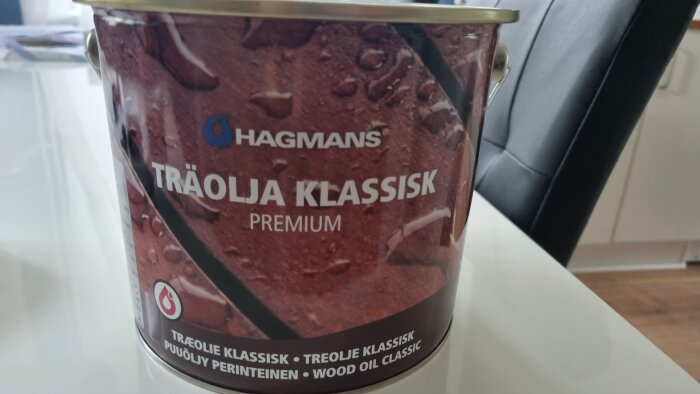 En burk med texten "Hagmans Träolja Klassisk Premium" mot en oskarp inredningsbakgrund.