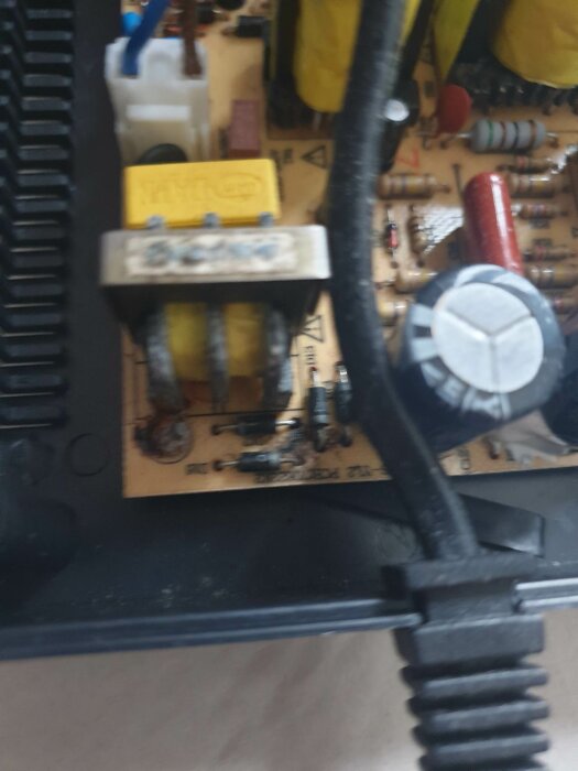 Oskarp bild av ett elektroniskt kretskort med komponenter och kondensatorer, troligen från en apparat eller maskin.