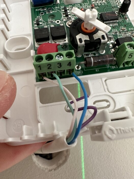 Elektronisk kretskort ansluter till kablar i plastklämma, handhållen vid installation eller reparation.
