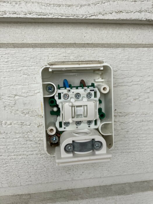 Öppen strömbrytare visar interna komponenter på en vit vägg. Elektricitet, installation, säkerhet, teknik.