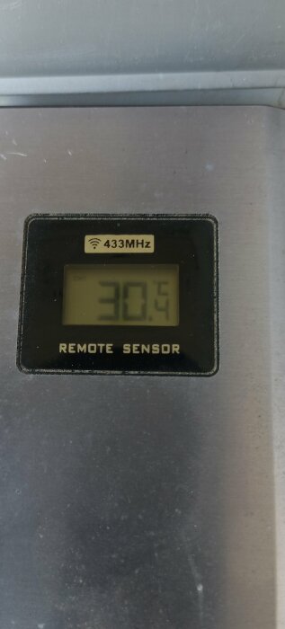 Digital display showing 30.5 degrees, labeled "REMOTE SENSOR," operates at 433MHz frequency. Appears to be a temperature monitor.