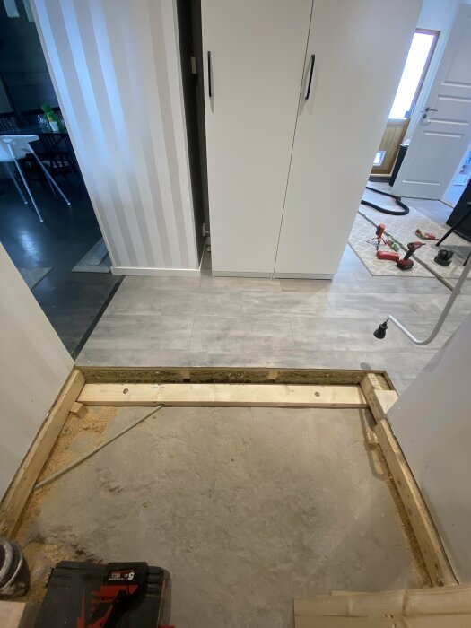 Renovering pågår, golv avlägsnat, synlig träram och verktyg, inomhusmiljö.