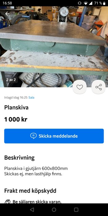 En planskiva i gjutjärn säljes, grönt underrede, i en verkstadsmiljö, med bakgrund av en motorcykel och verktyg.