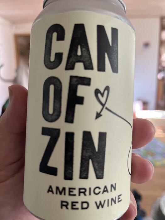 En burk rött vin med texten "CAN OF ZIN American Red Wine" hålls i en hand.