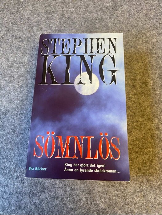 Stephen King-bok, "Sömnlös", liggande på texturerad yta, skumringsfärgad himmel och måne, tagline nedtill.