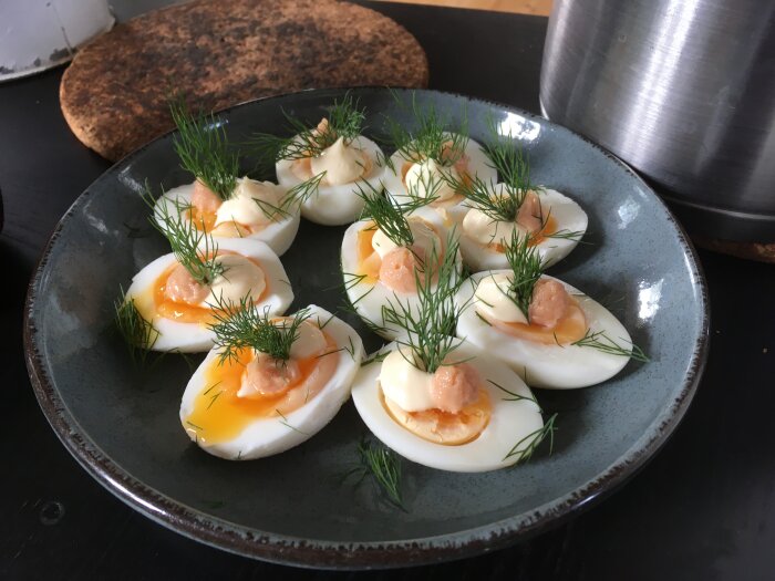 Halverade ägg med löstorka gulor och löjrom toppade med dill på en stengods tallrik.
