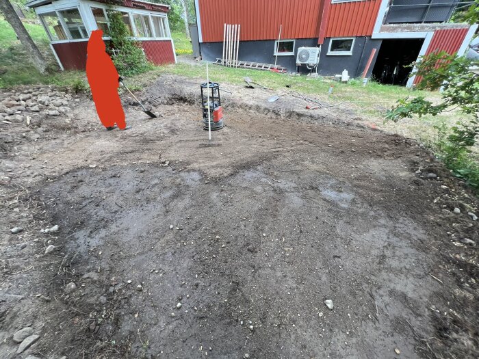 Grävd mark nära byggnad, spade, stenar, trädgårdsarbete eller anläggningsprojekt, externt värmepumpssystem, högar av jord.