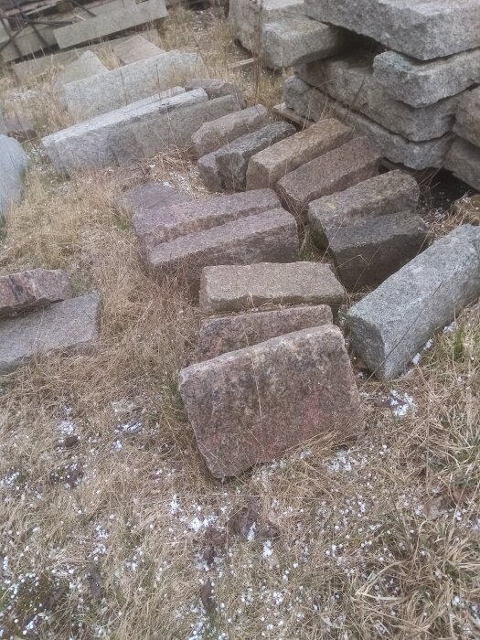 Stenhögar, utspridda granitblock, dött gräs, sparsam snö, overksam byggarbetsplats eller stenbrott.