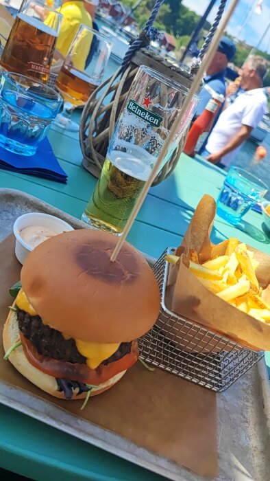 En burgare och pommes frites på ett café, ölglas, sommardag, uteservering, avslappnad atmosfär.