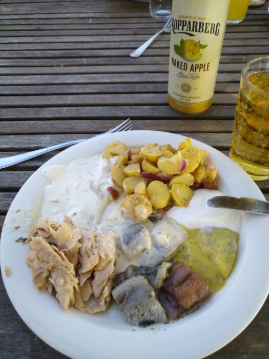 Middag utomhus: stekt potatis, kyckling, sås, och en flaska Kopparberg Naked Apple-cider.