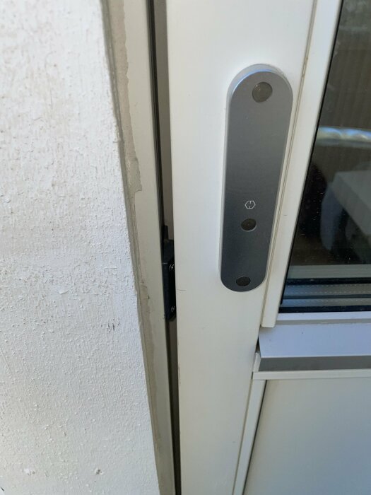 Dörr med digitalt lås och kodpanel på vit dörrkarm nära fönster.