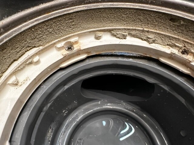 Tvättmaskinens sigill med smuts, tätning skadad, underhåll behövs, närbild.