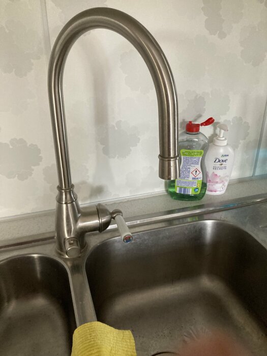 Köksdiskbänk med kran, tvättsvamp, handsåp och diskmedel.