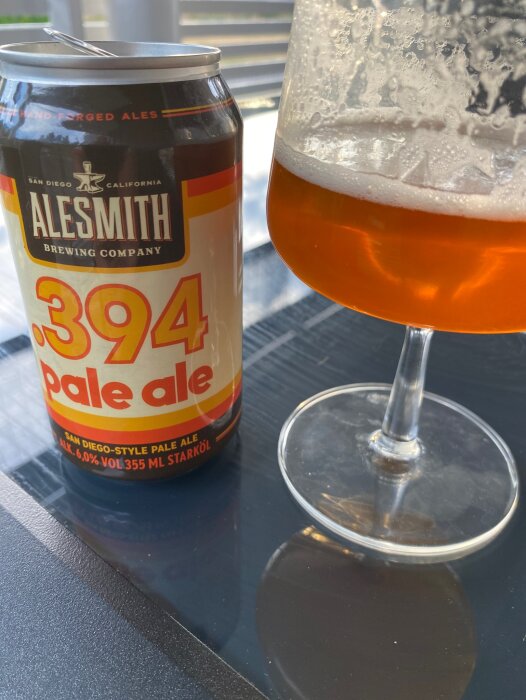 Ölburk och glas med amberfärgad ale på genomskinligt bord, utomhusljus, Alesmith 394, skumrester.