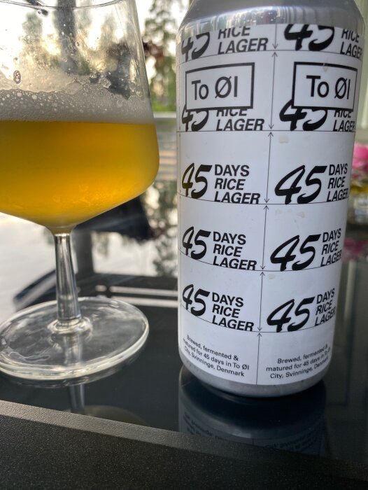 Ett glas med öl och en ölburk märkt "45 Days Rice Lager" från To Øl, Danmark.