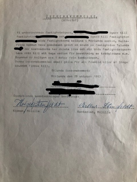 Fotografi av ett dokument, ser ut som ett officiellt avtal eller kontrakt, undertecknat och daterat 1983, text maskerad för sekretess.