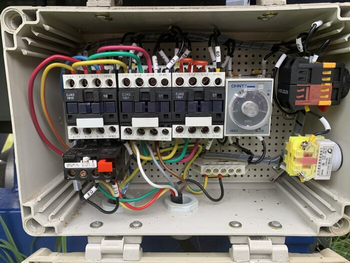 Elektriskt skåp med kontaktorer, säkringar, tidsrelä och kabelanslutningar i industriell installation.