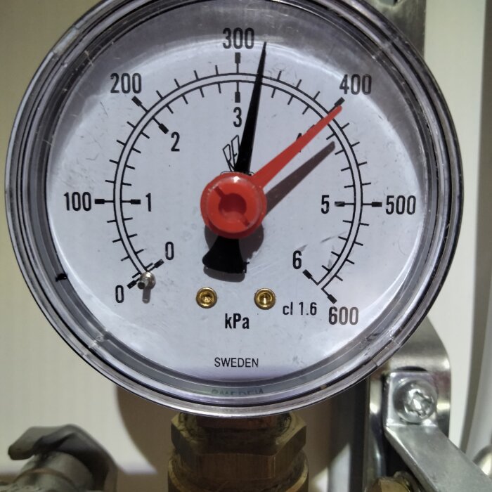 Manometer med skalor i kPa, PSI, ansluten till någon form av rör eller ventilsystem, märkt med "SWEDEN".