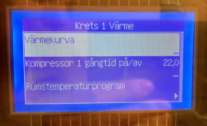 LCD-display visar meny för uppvärmningssystem: värme, varmekurva, kompressor, rumstemperaturprogram. Blå bakgrund, pixlig text.