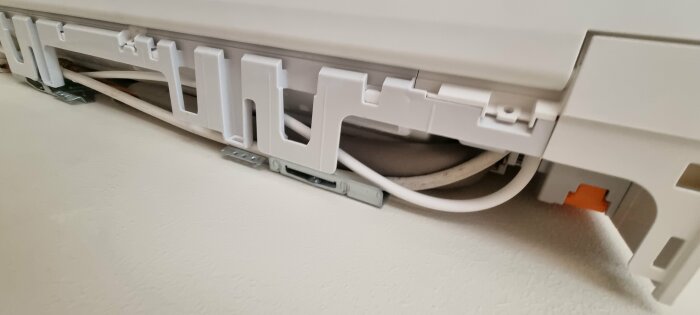 Kabelkanal med öppet lock visar inneslutna el- och nätverkskablar på en vit vägg.