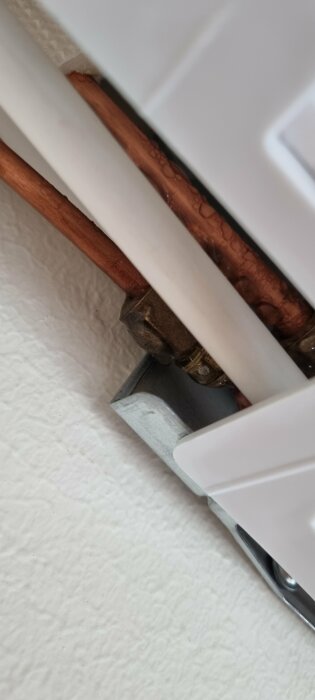 Vattenrör och radiatorfäste i en vägg, närbild, inomhus, byggdetaljer, fokus på röranslutning.