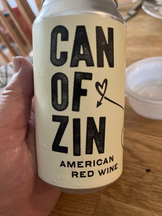 Person håller en burk märkt "CAN OF ZIN" med texten "AMERICAN RED WINE".