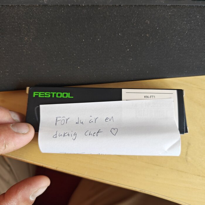 Lapp med texten "För du är en duktig chef" och ett hjärta, placerad på verktygslåda från Festool.