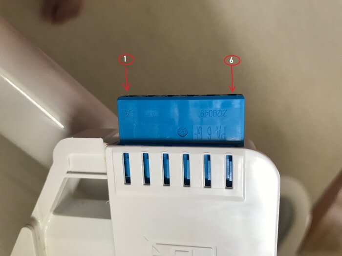 En blå uppladdningsbart batteri är felvänd ovanpå en vit laddare. Röd cirkel markerar orienteringen.