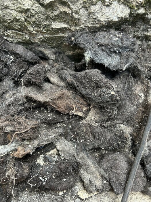 Gamla, slitna textilier och rep mot sten, fyllda med damm och skräp.