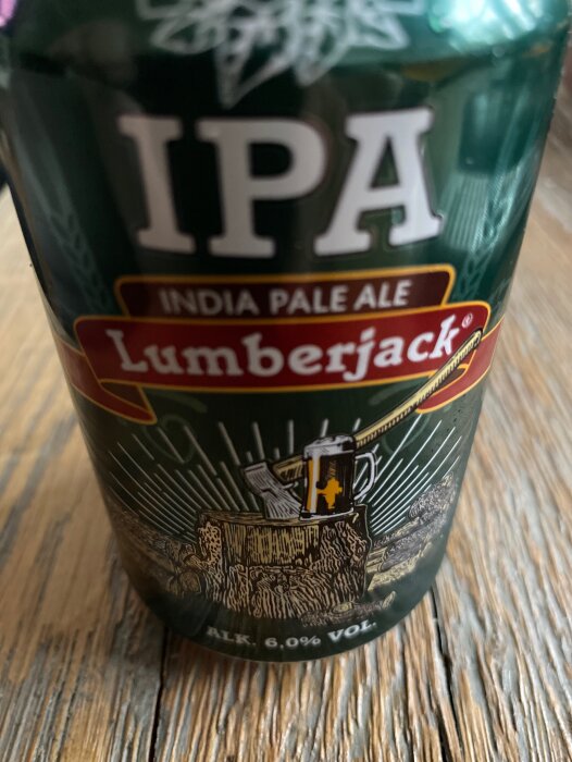 Ölflaska märkt "IPA Lumberjack", trä-tema, alkoholhalt skrivs ut, närbild, suddig bakgrund.