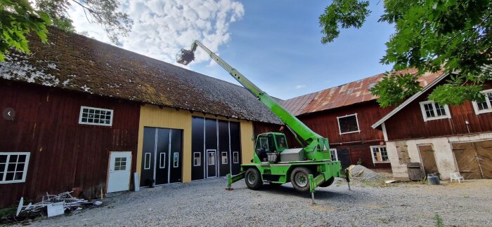 Traditionell röd lada, grön saxlift, grusgård, takarbete, landsbygd, soligt väder, gröna träd, delvis grästak.