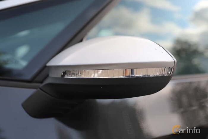 Ytterbackspegel på bil med integrerat blinkersljus, reflektion av himmel och träd, närbild.