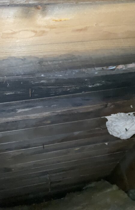 Mörkt utrymme, träväggar, ventilationsöppning, spindelväv, dammigt, övergivet utseende, dolt loft eller källare.