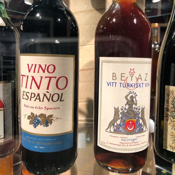Två vinflaskor, en spansk rödvin, en turkiskt vitvin, etiketter på svenska.