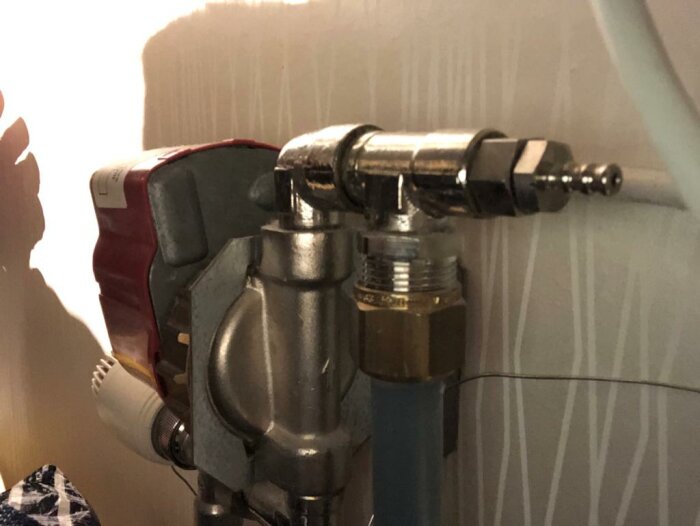 Borrkoppling på värmesystem, metalliska detaljer, grå bakgrund, teknisk utrustning, installation, röranslutning.