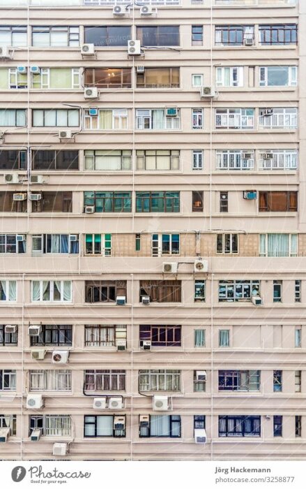 Fönster och balkonger på en hög bostadsbyggnad med många luftkonditioneringsapparater.