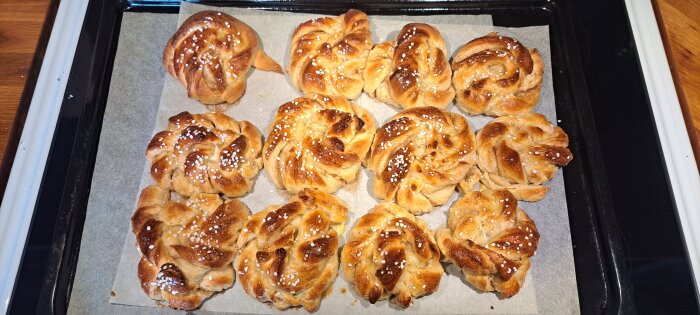 Nybakt, flätade kanelbullar på ett ugnsgaller, strösslade med pärlsocker.