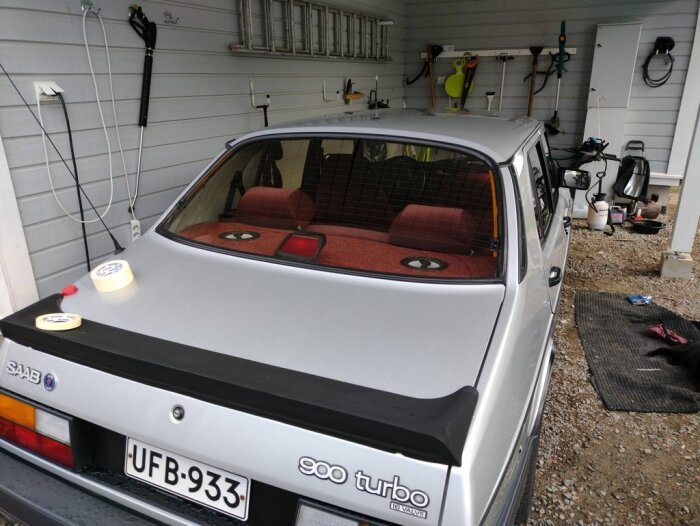 Silverfärgad Saab 900 Turbo i garage, röd inredning, verktyg på väggen, tejp på bagageluckan.