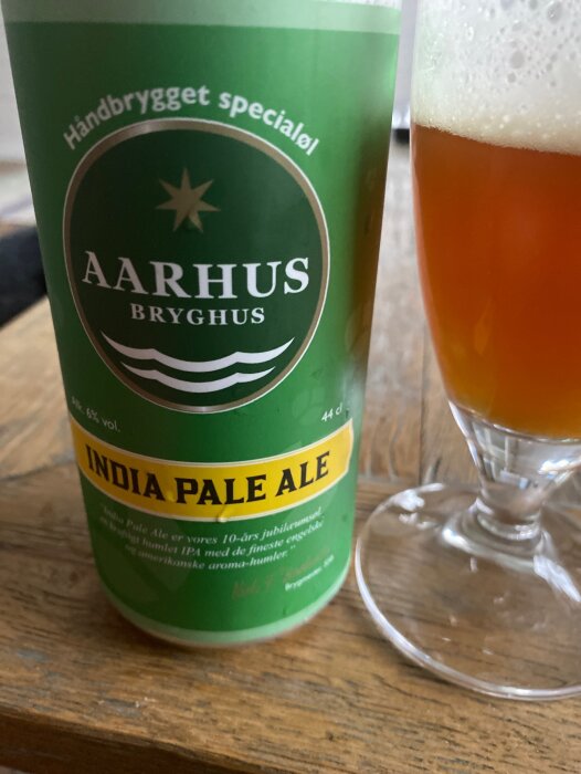 En ölburk med märket "Aarhus Bryghus" bredvid ett glas med ljus öl.