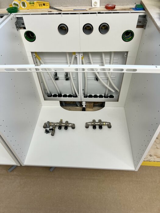 Laboratoriebänk under konstruktion med rör och ventiler, verktyg synliga, ofärdig installation.