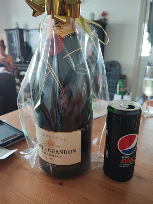 En flaska Moët & Chandon Champagne inpackad i genomskinlig cellofan med en burk Pepsi Max vid sidan.