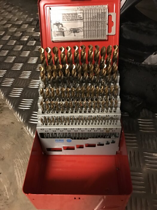 Ett uppsättning av borrbitar i olika storlekar förvarade i en röd metallåda.
