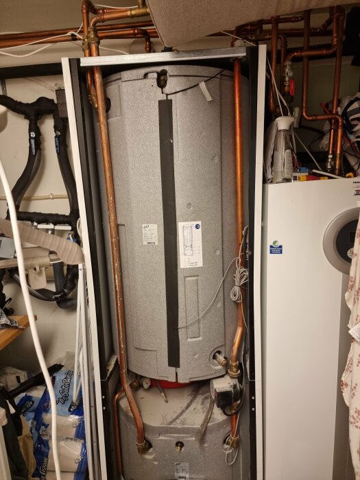 Värmesystem med varmvattenberedare, kablar och rör i ett tekniskt utrymme.